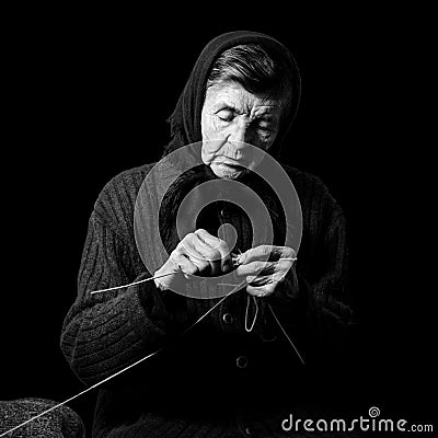 Grandma knitting. Black-and-white low key photograph on black background. Stock Photo