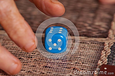 Grandma rolls a blue dice.Social game. Throwing a blue cube Stock Photo