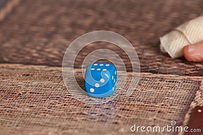 Grandma rolls a blue dice.Social game. Throwing a blue cube Stock Photo