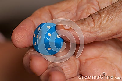 Grandma rolls a blue dice.Social game. Throwing a blue cube Stock Photo