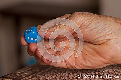 Grandma rolls a blue dice.Social game. Throwing a blue cube Stock Photo