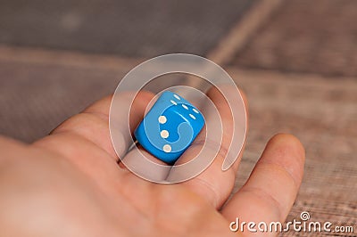 Grandma rolls a blue dice.Social game. Throwing a blue cube Stock Photo