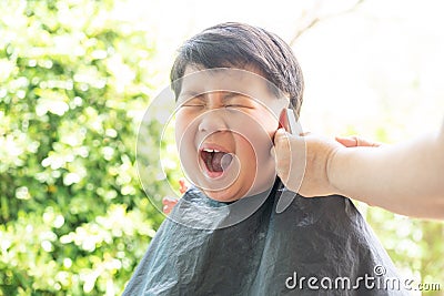 Grandma was cutting hair for her nephew at home in the garden Stock Photo