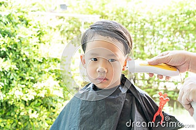 Grandma was cutting hair for her nephew at home in the garden Stock Photo