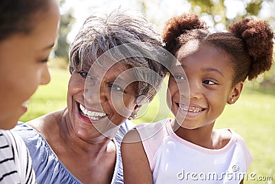 Grandmother With Adult Daughter And Granddaughter Relaxing In Park Stock Photo