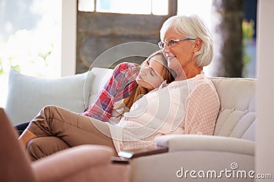 Grandmother With Adult Granddaughter Watching TV On Sofa Stock Photo