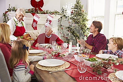 Grandmother Bringing Out Turkey At Family Christmas Meal Stock Photo