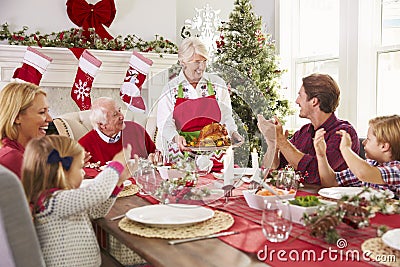 Grandmother Bringing Out Turkey At Family Christmas Meal Stock Photo