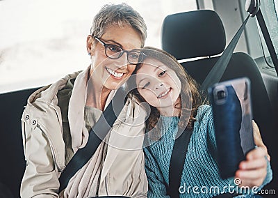 Grandmother, girl and selfie with phone in a car while on a road trip for social media post online. Senior woman and kid Stock Photo