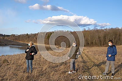 Grandmother and grandchildren in medical masks are walking with a tape measure in their hands observing a safe distance Stock Photo