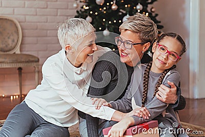 Grandmother and granddaughter decorating a Christmas treeFamily gathered around a Christmas tree, female generations Stock Photo