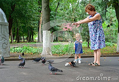 Grandmother and granddaughter feed pigeons Stock Photo