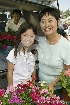 Grandmother and granddaughter with flowers by back of SUV portrait Stock Photo