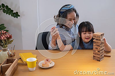 Grandmother and granddaughter play games. Blockwood Puzzle To develop skills for granddaughter and as a holiday activity Stock Photo