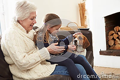 Grandmother And Granddaughter Relaxing At Home With Pet Dog Stock Photo