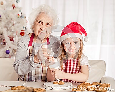 Grandmother with granddaughter holding baked cookie Stock Photo