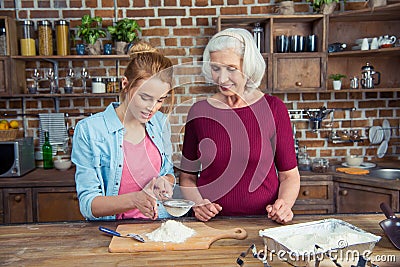 Grandmother and granddaughter sifting flour Stock Photo