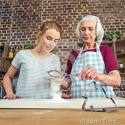 Grandmother and granddaughter sifting flour Stock Photo