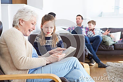 Grandmother And Granddaughter Using Digital Tablet Together Stock Photo