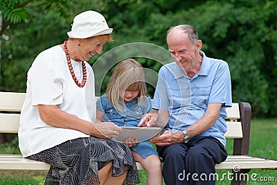 Grandmother, grandfather and granddaughter using tablet Stock Photo