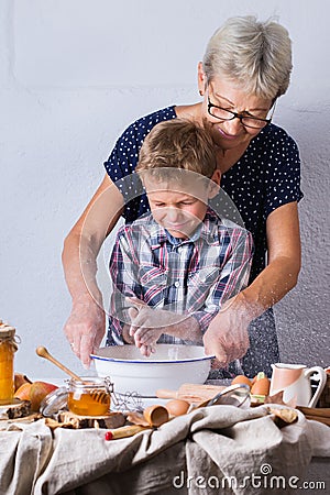 Grandmother with grandson cooking, kneading dough, baking in the kitchen Stock Photo