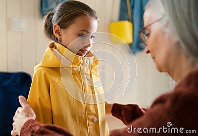 Grandmother helping granddaughter to get ready to leave home for school. Stock Photo