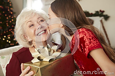 Grandmother Receiving Christmas Gift From Granddaughter At Home Stock Photo