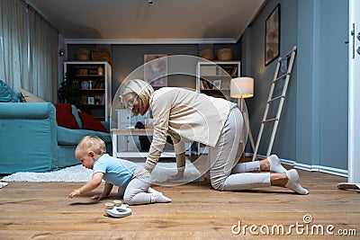 Grandmother taking care of her grandchild while his parents working. Senior woman work as a nanny, playing with young baby on the Stock Photo