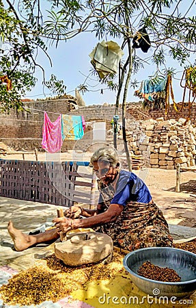 grandmother working on old stone wheel flour mill and making chickpeas wheat. Editorial Stock Photo