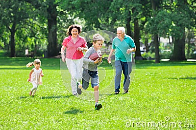 Grandparent And Grandchildren Playing Rugby In The Park Stock Photo