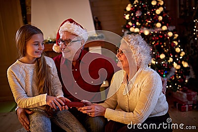 Grandparents giving gifts granddaughter at Christmas eve Stock Photo