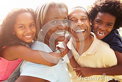 Grandparents Giving Grandchildren Piggyback Ride In Garden Stock Photo