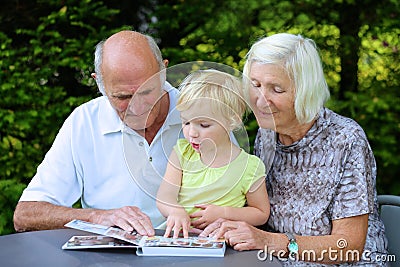 Grandparents with grandchild watching photo album Stock Photo