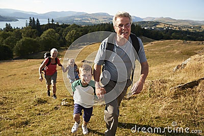 Grandparents With Grandchildren Climbing Hill On Hike Through Countryside In Lake District UK Together Stock Photo