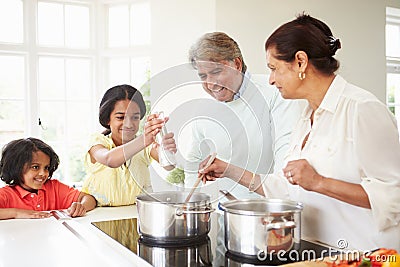 Grandparents And Grandchildren Cooking Meal At Home Stock Photo