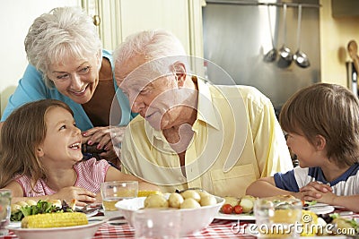 Grandparents And Grandchildren Eating Meal Together In Kitchen Stock Photo