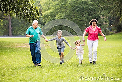 Grandparents And Grandchildren Running In Park Stock Photo