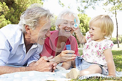 Grandparents And Granddaughter Playing In Park Together Stock Photo