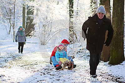 Grandparents playing with grandchildren in winter forest Stock Photo