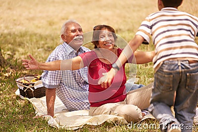 Grandparents Senior Couple Hugging Young Boy At Picnic Stock Photo