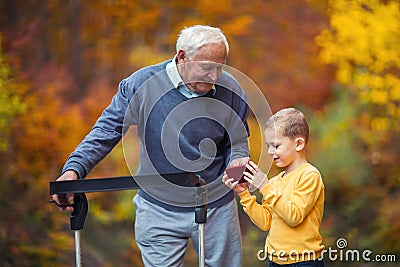 Grandson showing something on phone in the park disabled senior grandfather Stock Photo