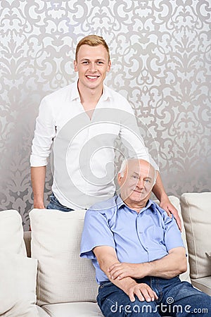 Grandson standing behind his grandfather Stock Photo