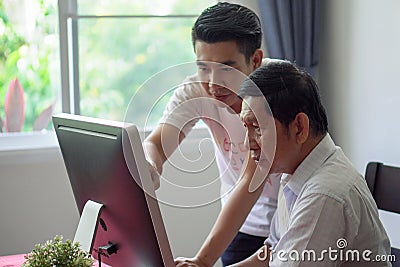 Grandson teaching grandfather how to Using computer and technology in home . young Teacher help senior Man learning to connect Stock Photo