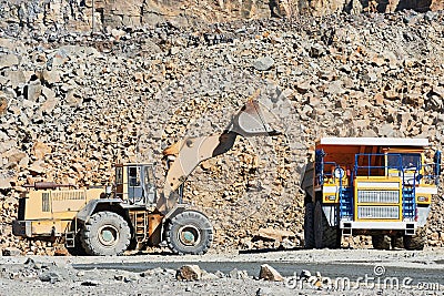 Granite mining. Wheel loader loading ore into dump truck at opencast Stock Photo