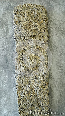 A granite pillar protrudes from a reinforced concrete wall. Stock Photo