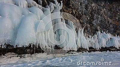 The granite rock at the base is covered with ice splashes, icicles like lace frills. Stock Photo