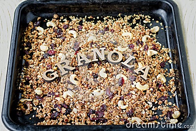 Granola in a black baking sheet. The inscription in wooden letters Granola Stock Photo