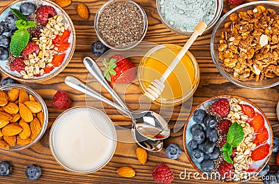 Granola bowl with yogurt and fresh almonds, blueberries, raspberries,peach and strawberries on kitchen table. Stock Photo