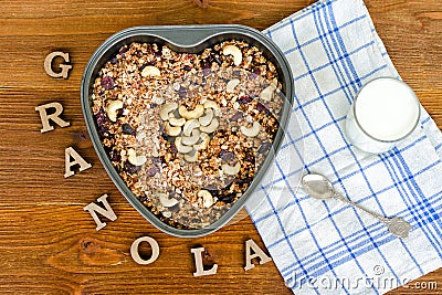 Granola in a heart-shaped baking dish. Yogurt, towel, inscription Granola wooden letters. Food Concept Stock Photo