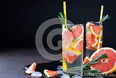 Grapefruit lemonade. Two glasses of refreshing drink, water with grapefruit, rosemary branches and ice. Stock Photo